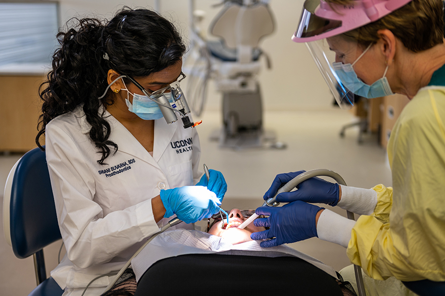 Prosthodontist and dental assistant examine a model patient